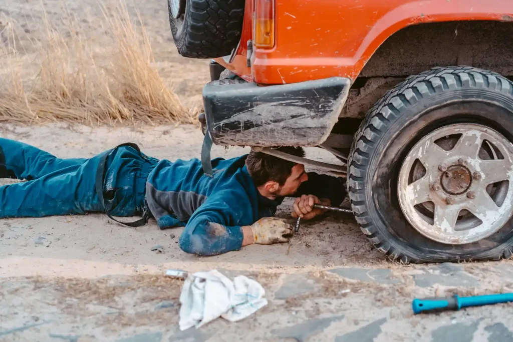 Man lies under a 4x4 car and repairing, lemonlawassist