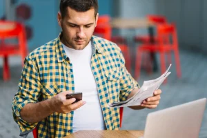 Man posing with phone and document, lemonlawassist