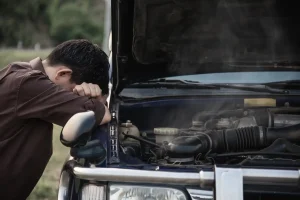 Man try to fix a car engine problem on a local road, lemonlawassist