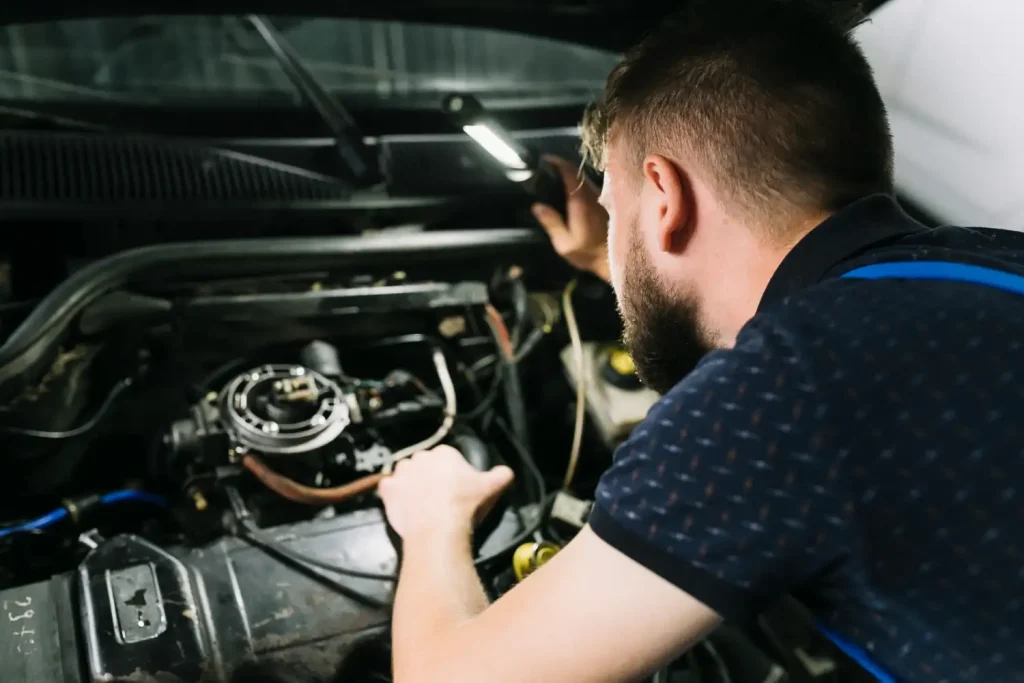 Repairmen inspecting vehicle engine, lemonlawassist