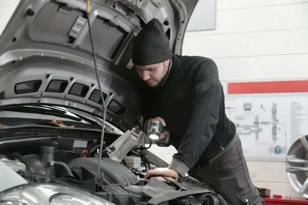 Man in black jacket and black knit cap inspecting car engine