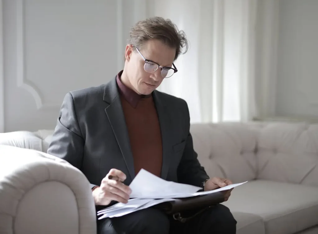 Classy male lawyer reading papers on couch, lemonlawassist