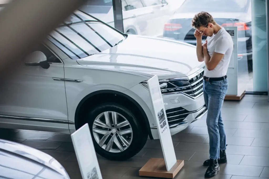 Man looking for a car in a car showroom, lemonlawassist