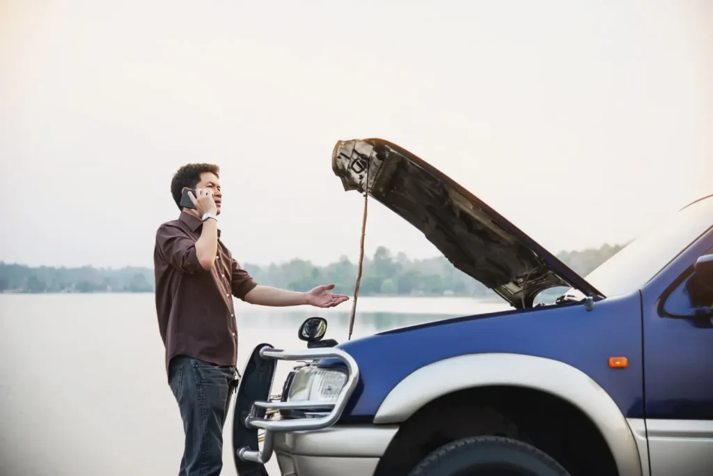 Man try to fix a car engine problem on a local road, lemonlawassist