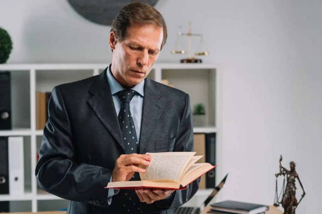 Mature lawyer turning pages of law book in the courtroom, lemonlawassist