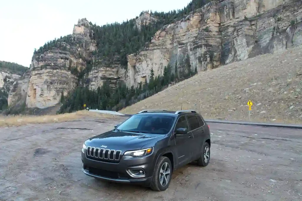 A sleek, black Jeep parked near a scenic mountain, lemonlawassist