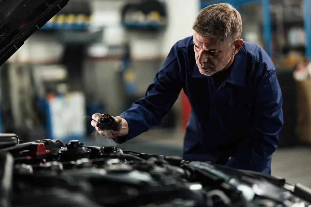 Auto mechanic opening radiator cap while repairing car in a repair shop, lemonlawassist