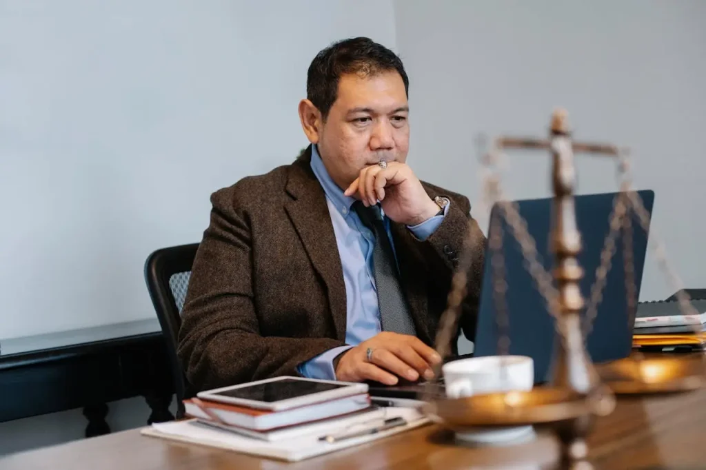 Contemplative lawyer working on laptop in law firm, lemonlawassist