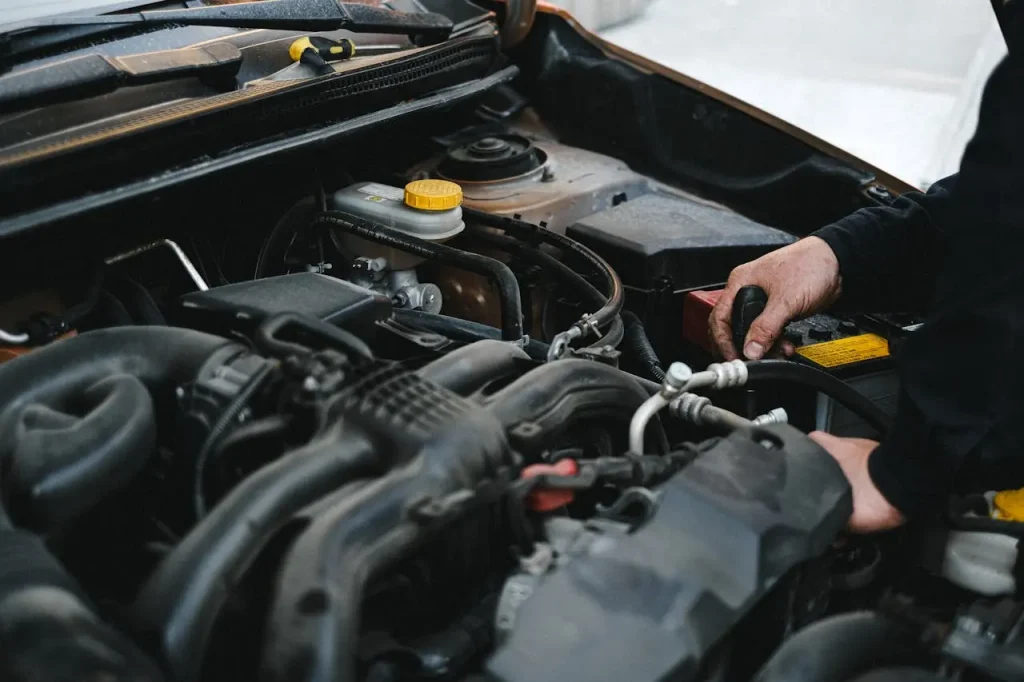 Person in black jacket working on the engine of the car, lemonlawassist