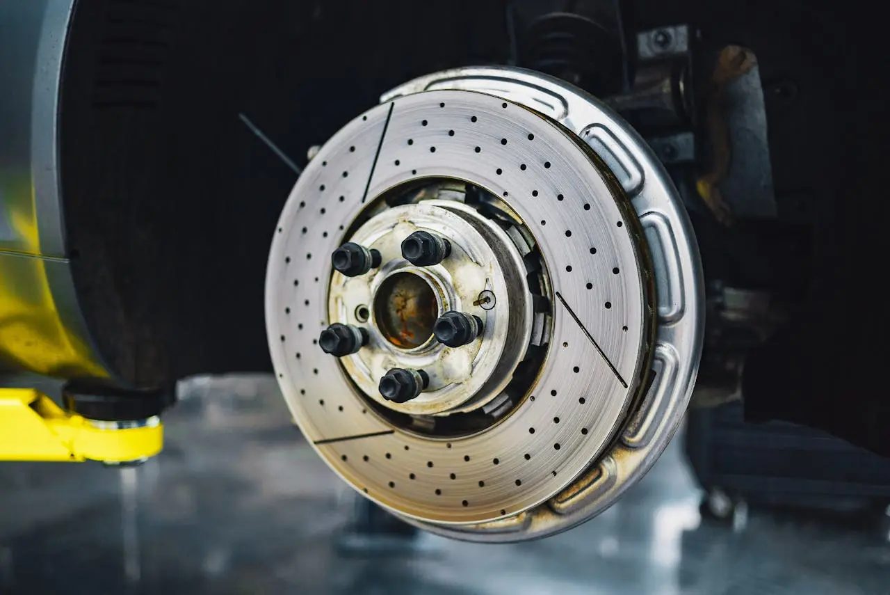 Close-up image of a ventilated and drilled car brake disc with the hub assembly, showcasing its detailed surface, lemonlawassist