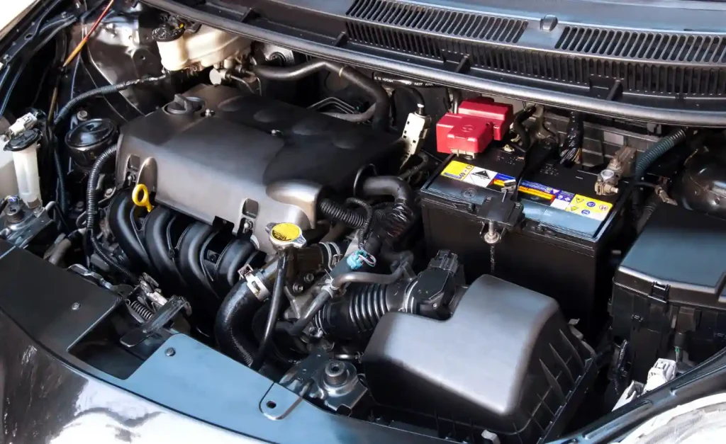 Close-up of a car engine and battery inside the engine bay, illustrating automotive components and maintenance, lemonlawassist