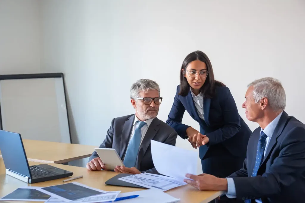 Professional lawyers meeting with two senior male and a young female colleague discussing documents and plans in a modern office setting, lemonlawassist