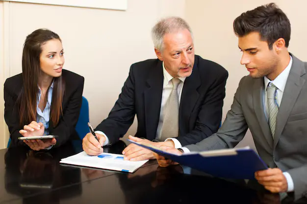 Professionals lawyers collaborating at a desk, reviewing documents and discussing project details, lemonlawassist