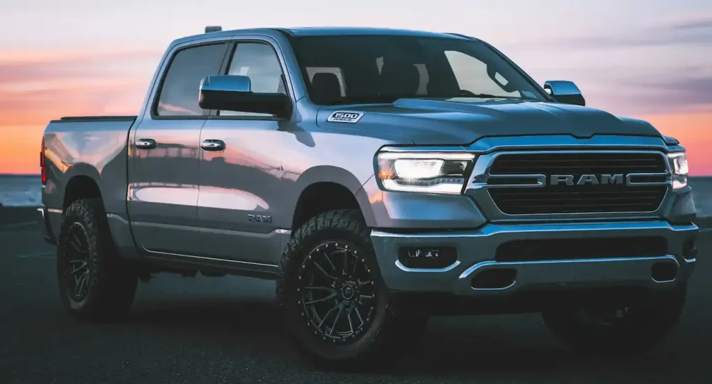 Silver RAM 1500 pickup truck parked by the beach at sunset, highlighting rugged design, durability, lemonlawassist