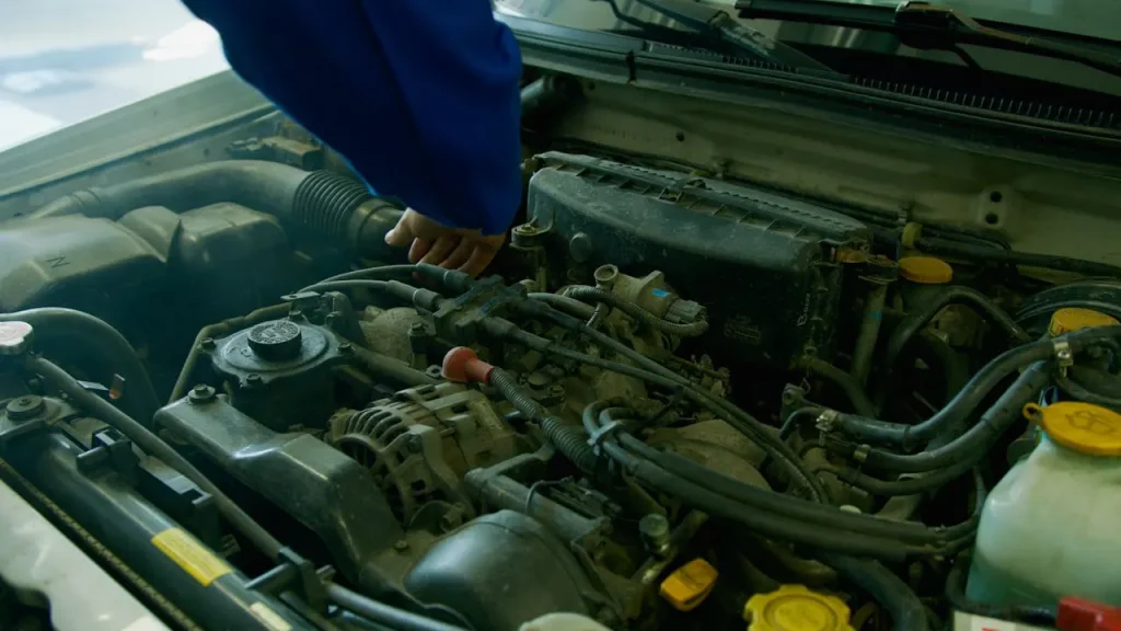 Mechanic inspecting a car engine in a workshop, focusing on engine components and maintenance, lemonlawassist