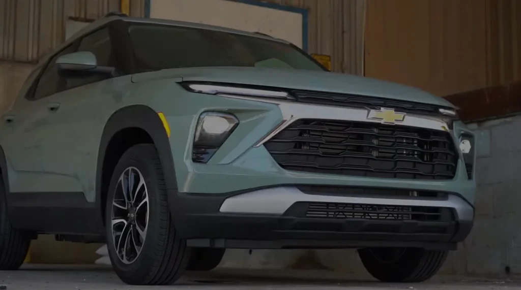 A Chevrolet SUV in a light green color, parked indoors with the front grille and headlights prominently displayed, lemonlawassist