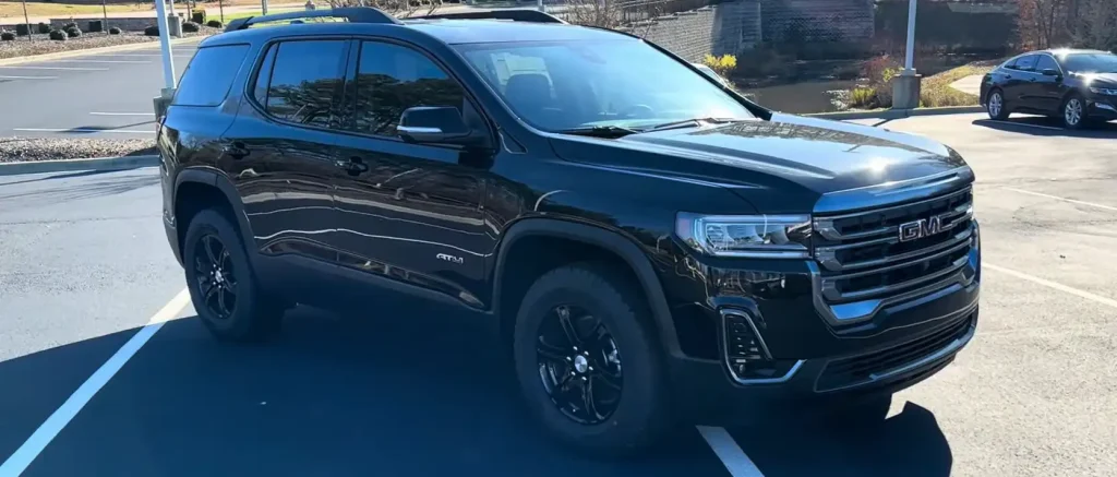Black GMC SUV with rugged off-road tires parked in an outdoor lot, reflecting sunlight on its glossy exterior, lemonlawassist