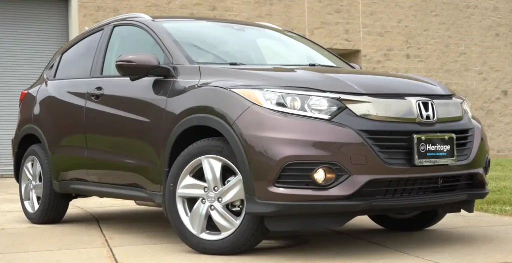Front-side view of a brown Honda HR-V parked outdoors, showcasing its sleek design and polished exterior with visible headlights and wheels, lemonlawassist