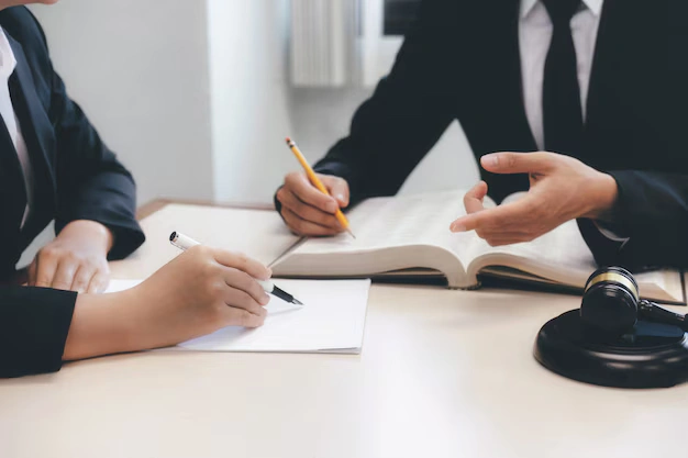Professional lawyers in a modern law firm, engaged in a team meeting, discussing legal strategies and case details, lemonlawassist