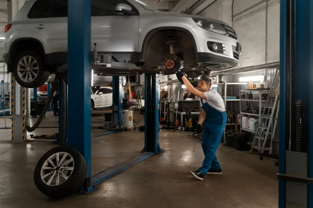 Auto mechanic inspecting a car's suspension in a professional garage, lemonlawassist