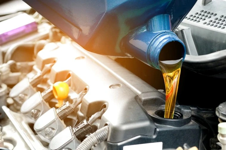 Close-up of motor oil being poured into a car engine during an oil change, lemonlawassist