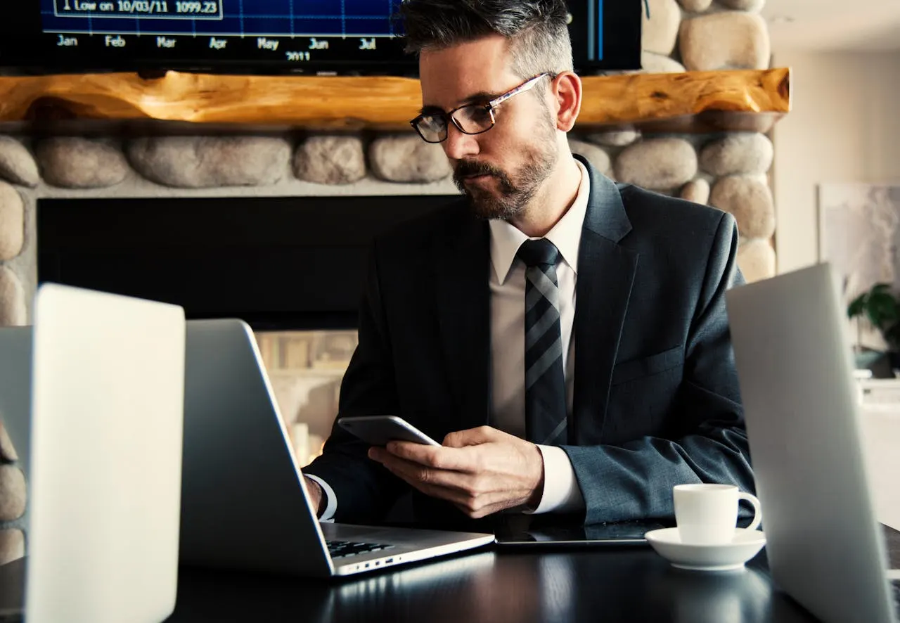 Lawyer professional in suit working on laptop and phone at modern office desk, lemonlawassist