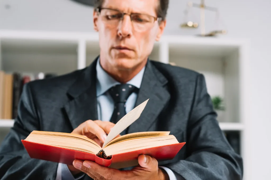 Male lawyer in a suit reading a legal book in his office, lemonlawassist