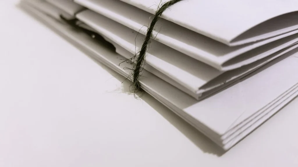 Stack of white envelopes tied together with green string, lemonlawassist