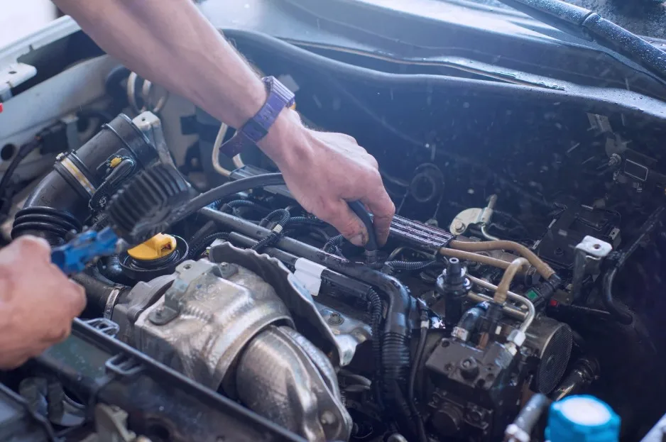 Hands of a technician repairing engine components under the hood, lemonlawassist