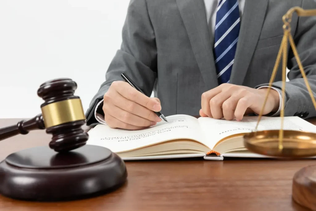 Lawyer writing in legal book with gavel and scales, lemonlawassist