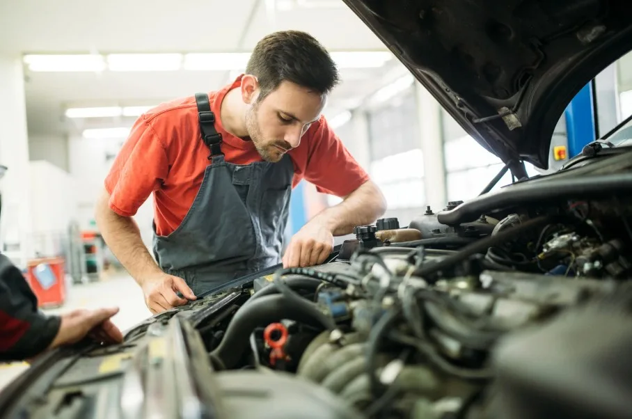 A mechanic inspecting a car's engine, symbolizing recurring defects and repair attempts that qualify a vehicle as a lemon.
