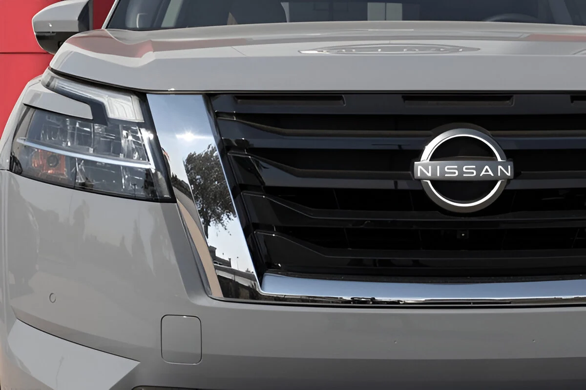 Close-up of a new gray Nissan SUV's front grille and emblem, indicating a modern vehicle that may qualify for Lemon Law assistance.